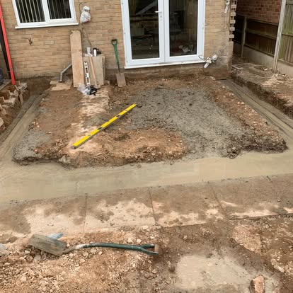 Concrete screed base being prepared behind brick house