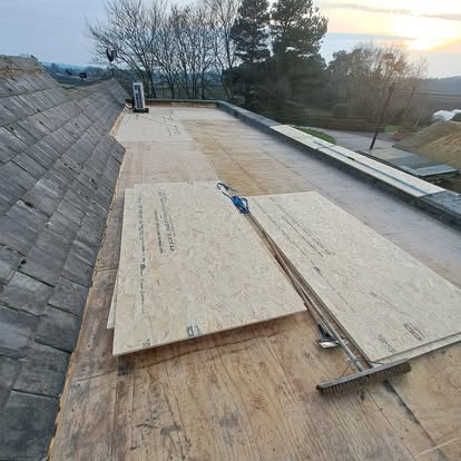 Flat roof OSB deck boards being laid at sunset