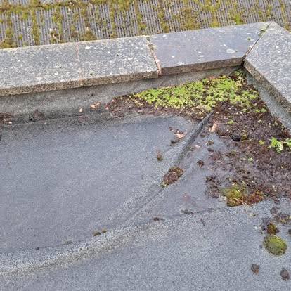 Damaged flat roof corner with concrete coping