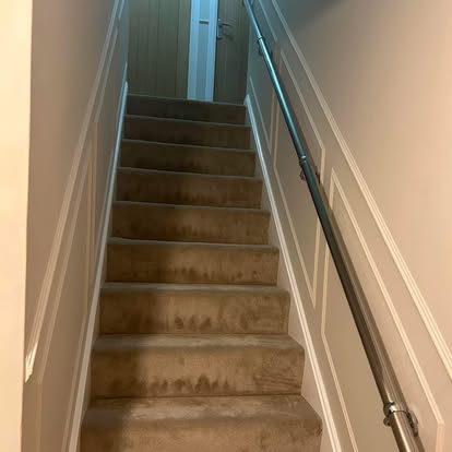 Staircase with panelled walls and chrome handrail