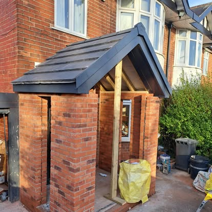 Brick porch under construction with grey tiled canopy