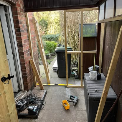 Dark brown lean-to under construction against brick wall
