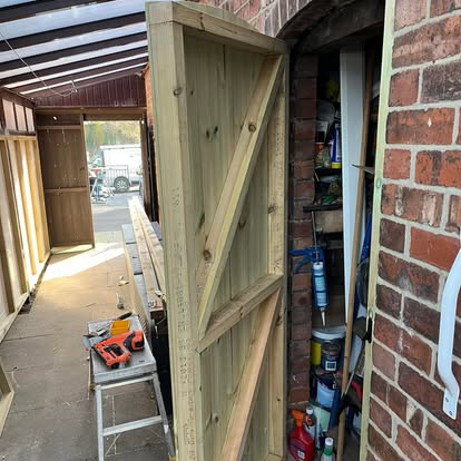 Timber ledge and brace door being fitted to lean-to
