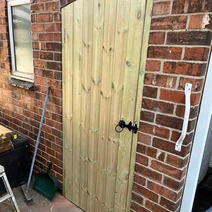 Natural timber gate with ring latch on brick wall