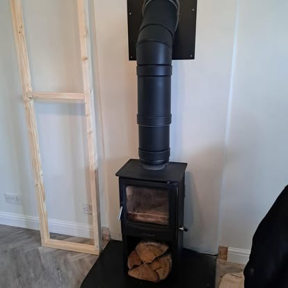 Wood burner stove with flue pipe and timber stud frame