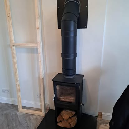 Wood burner with rising flue pipe and frame beside it
