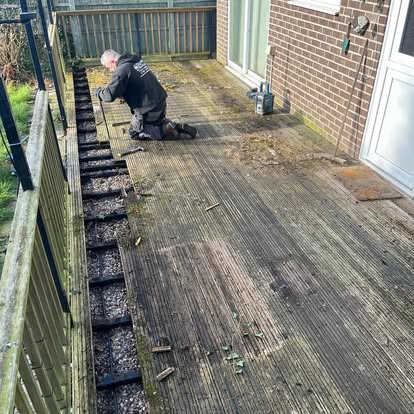 Worker removing old rotted decking with metal pergola frame