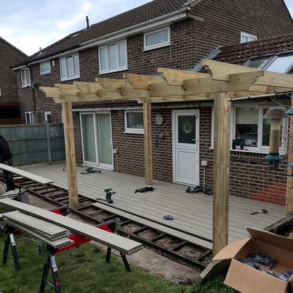 Composite decking boards being laid timber pergola frame