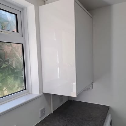 White gloss wall cabinet being fitted in utility room