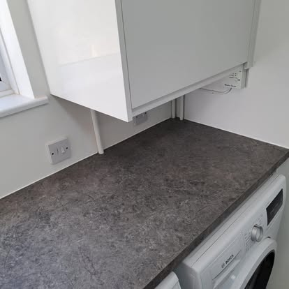 Completed utility room with dark worktop and appliances