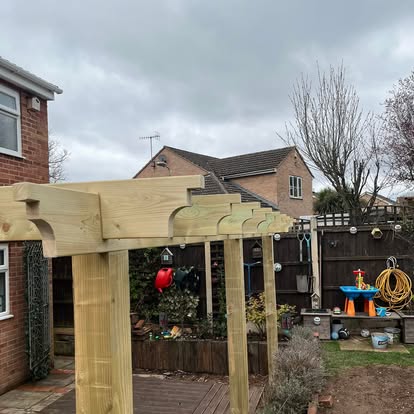 Completed timber pergola with scalloped brackets in garden