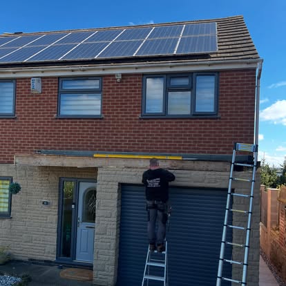 Worker on ladder fitting fascia on semi-detached