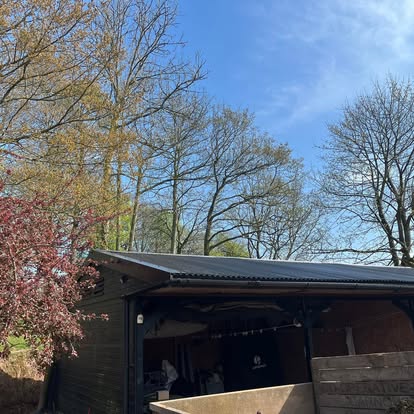 Completed black corrugated barn roof viewed from trees