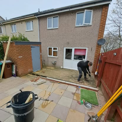 Worker removing old decking boards on grey terrace house