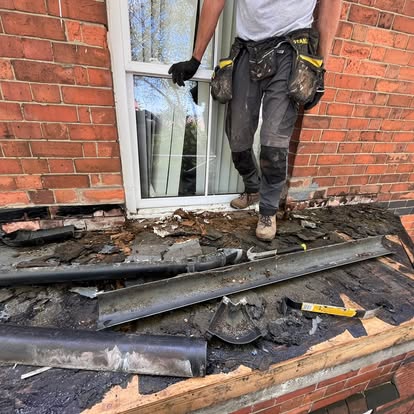 Worker stripping old felt from Victorian bay window roof