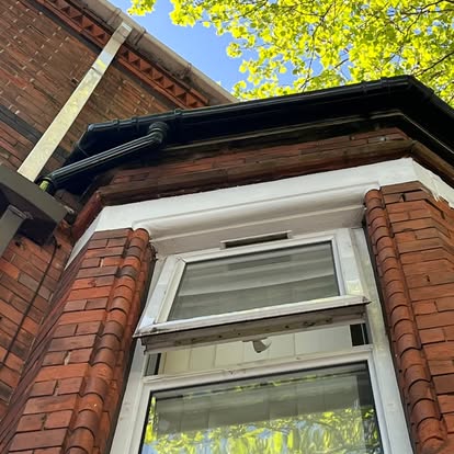 Victorian bay window with black guttering and white UPVC soffit