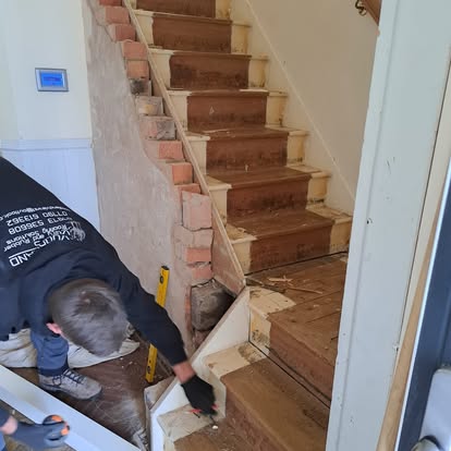 Worker at bottom of stairs with exposed brick stair wall