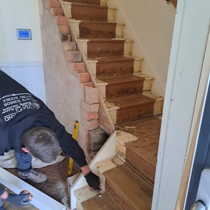 Worker stripping old staircase with exposed brickwork