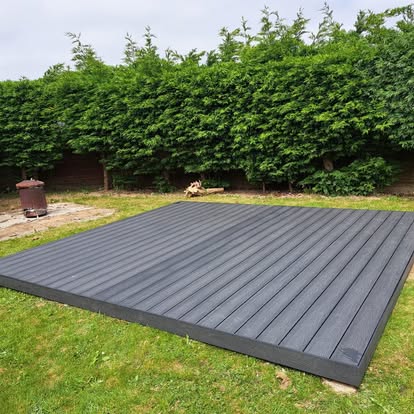 Completed grey composite flat deck in hedge garden