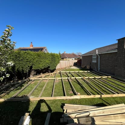 Deck joist grid laid across bungalow garden