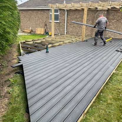 Worker laying composite boards with pergola behind