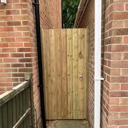 New vertical board timber side gate between brick walls