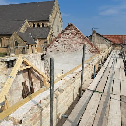 Stone building with scaffolding and new roof structure