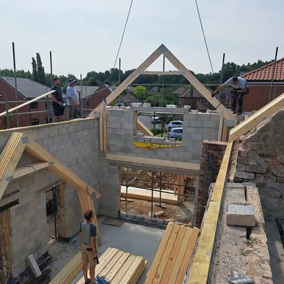 Roof trusses craned onto blockwork walls by workers