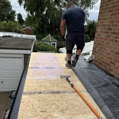 Worker applying adhesive to OSB deck before EPDM