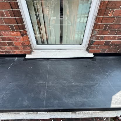 Small EPDM flat roof patch below window at brick house