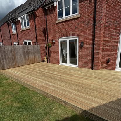 Wide timber deck behind brick house