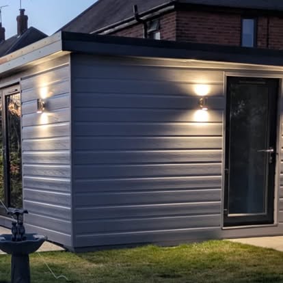 Grey-clad garden room lit up at dusk