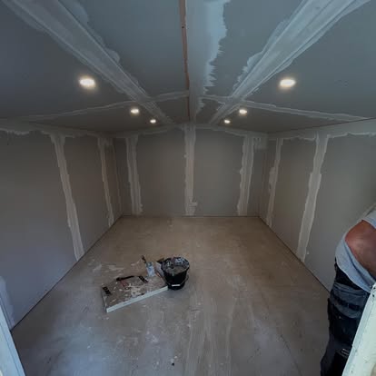 Plasterer skimming large garden room interior