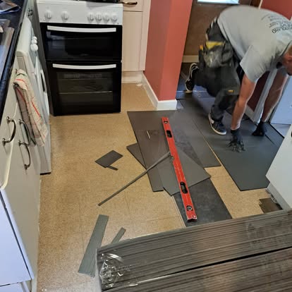 Dark grey vinyl flooring being laid in kitchen