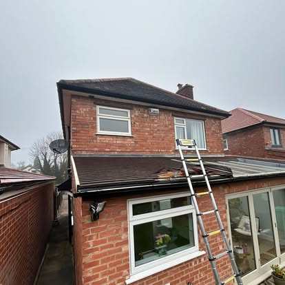 Brick house with ladder and damaged roof tiles
