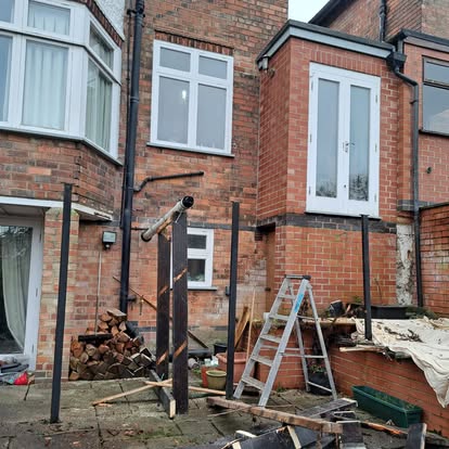 Dark steel post frame at rear of house, earliest stage